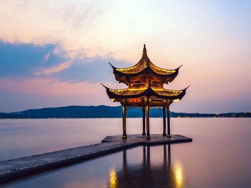 Hình ảnh Hồ Tây tại Hàng Châu lúc hoàng hôn, với ánh nắng vàng phủ lên mặt nước